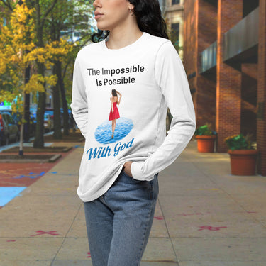 Long-sleeve Bella+Canvas t-shirt made from preshrunk ring-spun cotton with “Impossible Woman” design message, “The Impossible Is Possible with God,” inspirational apparel encouraging women to walk freely in God's incredible ways, woman downtown wearing white long-sleeve t-shirt